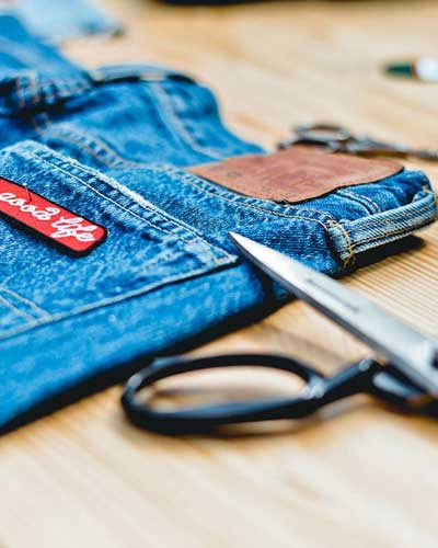 Uma pessoa tirando medida de uma barra de calça para realizar ajustes e reparos