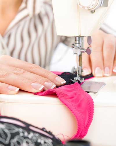 Mulher ruiva, ao seu fundo na parede, painel com lingerie.