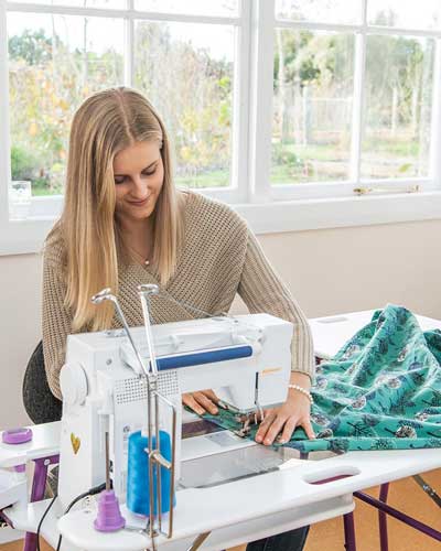Mulher costurando em máquina de costura doméstica.