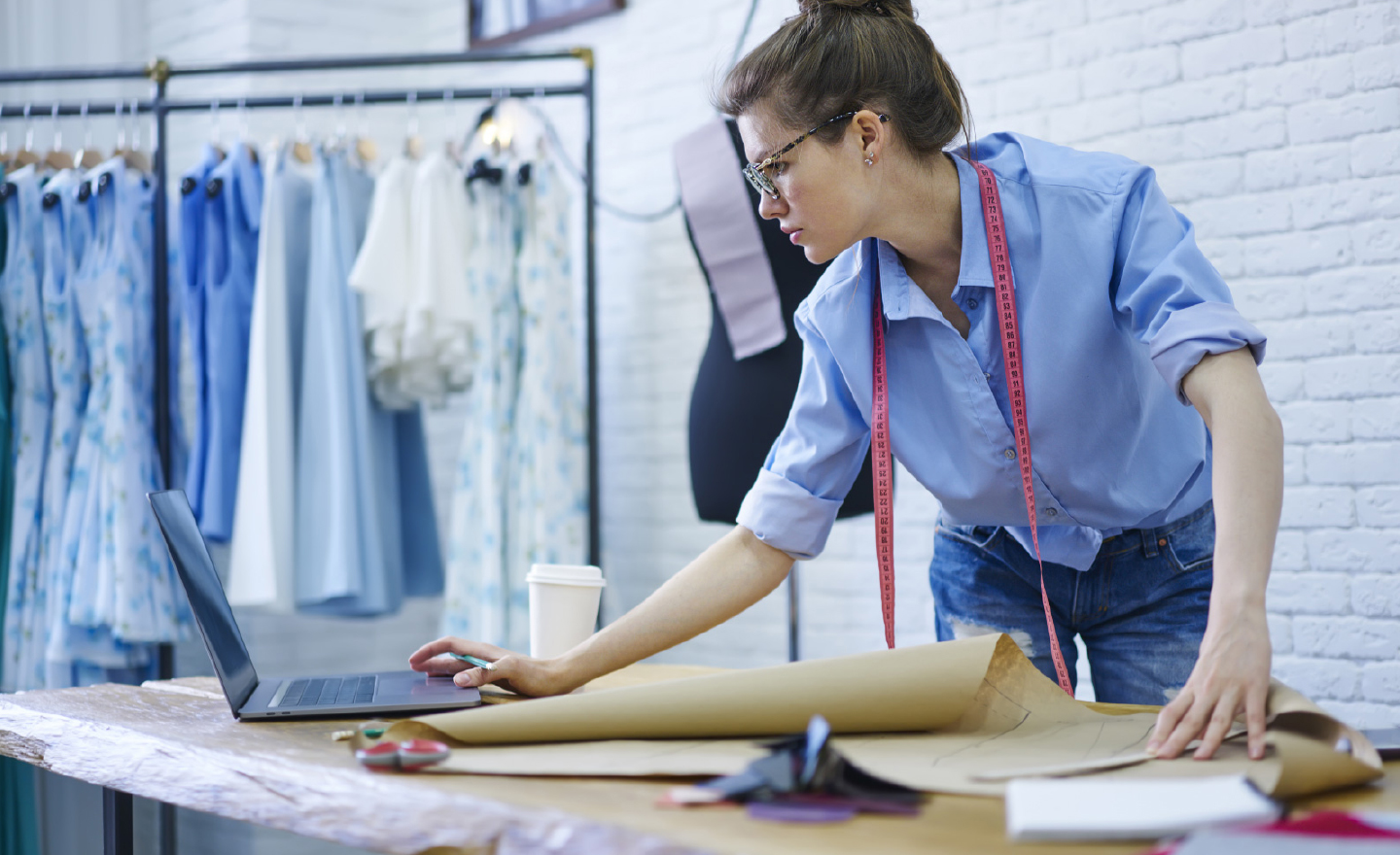 Mulher com camisa azul desenvolvendo ficha técnica de vestuário