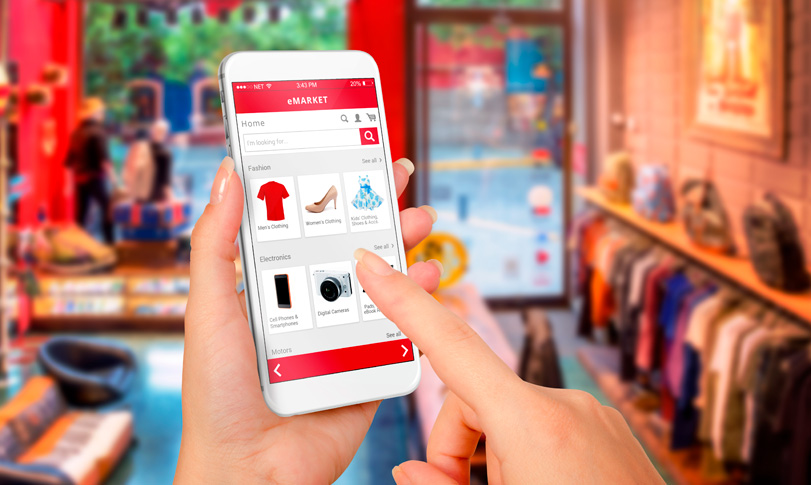 Curso de Varejo de Moda Uma loja de varejo de moda com uma pessoa acessando na palma da mão através de um celular